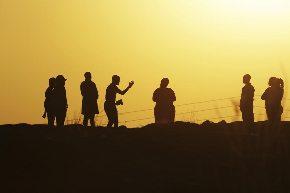 A preacher holds the bible while praying and worshipping to a group of followers atop a mountain in Harare, in this Friday, May 28, 2021 photo. As virus cases surge in the worlds poorest countries, there is growing sense of looming danger for millions of the unvaccinated,especially those who toil in the informal sector,living hand to mouth and inevitably pay cash when in health emergencies. (AP Photo/Tsvangirayi Mukwazhi)