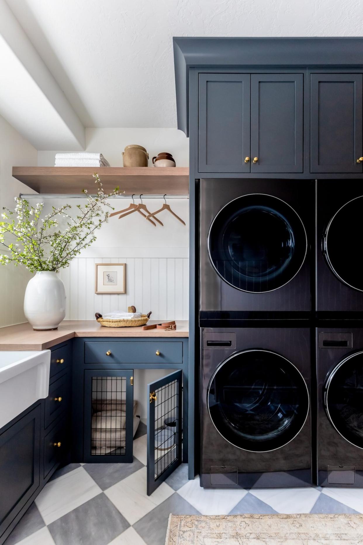 Laundry room with blue cabinets, wood counters, and stacked washer and dryer