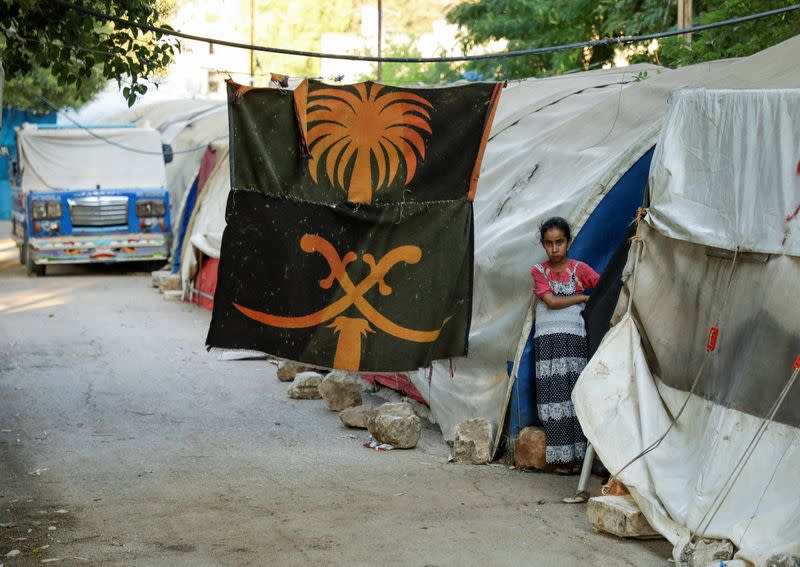 A girl stands outside a tent at a camp for internally displaced people in the opposition-held Idlib