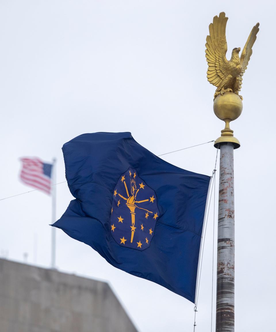 Indiana and U.S. flags fly in a stiff breeze in downtown Indianapolis as about an inch of snow falls on central Indiana, Sunday, Jan. 23, 2022. A little more snow could fall Monday morning. 