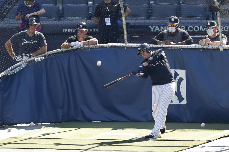 New York Yankees' Mike Tauchman, left, and Brett Gardner, second from left, watch as Gio Urshela bats in the cage during a baseball summer training camp workout Sunday, July 5, 2020, at Yankee Stadium in New York. (AP Photo/Kathy Willens)