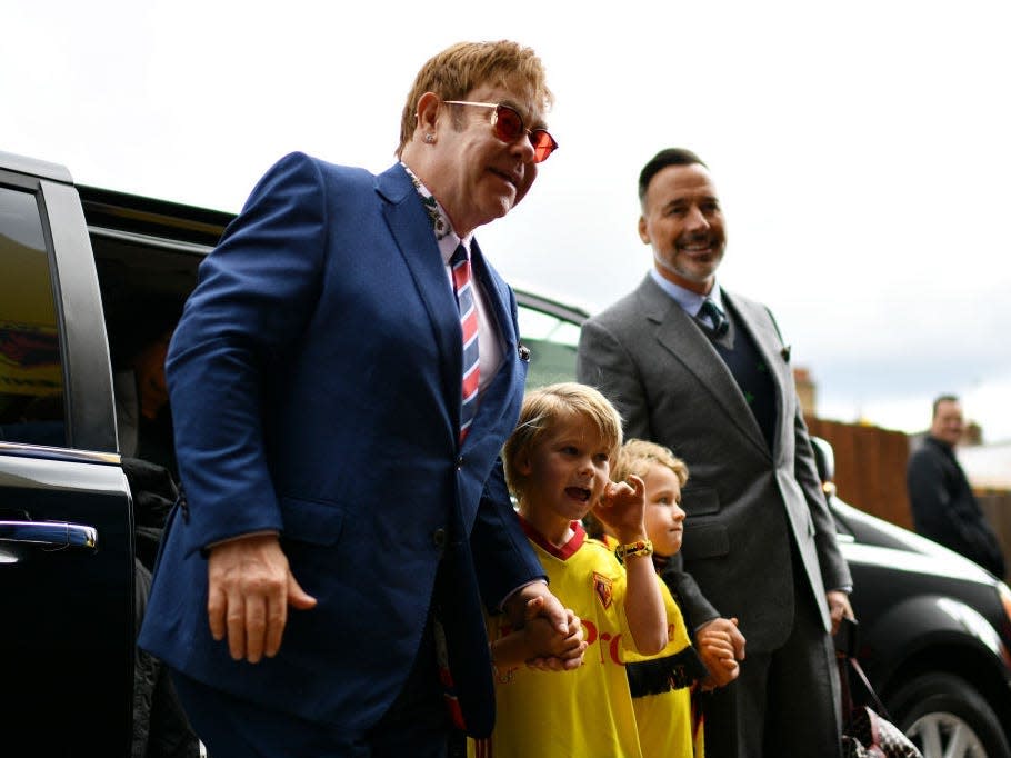 Elton John exits a car with his husband and sons.