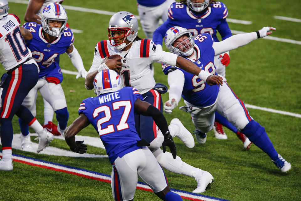 New England Patriots' Cam Newton (1) rushes past Buffalo Bills' Harrison Phillips (99) and Tre'Davious White (27) during the second half of an NFL football game Sunday, Nov. 1, 2020, in Orchard Park, N.Y. Newton fumbled the ball on the play. The Bills won 24-21. (AP Photo/John Munson)