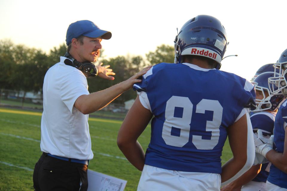 Perry head coach Bryce Pierce talks with Tyler Gomez before the start of a homecoming game against Des Moines Hoover on Sept. 16 in Perry.