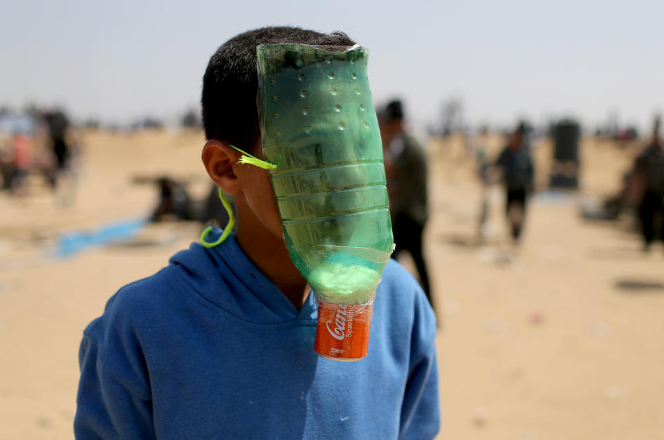 <p>A Palestinian protects himself from inhaling tear gas at the Israel-Gaza border during a protest demanding the right to return to their homeland, in the southern Gaza Strip, April 6, 2018. (Photo: Ibraheem Abu Mustafa/Reuters) </p>