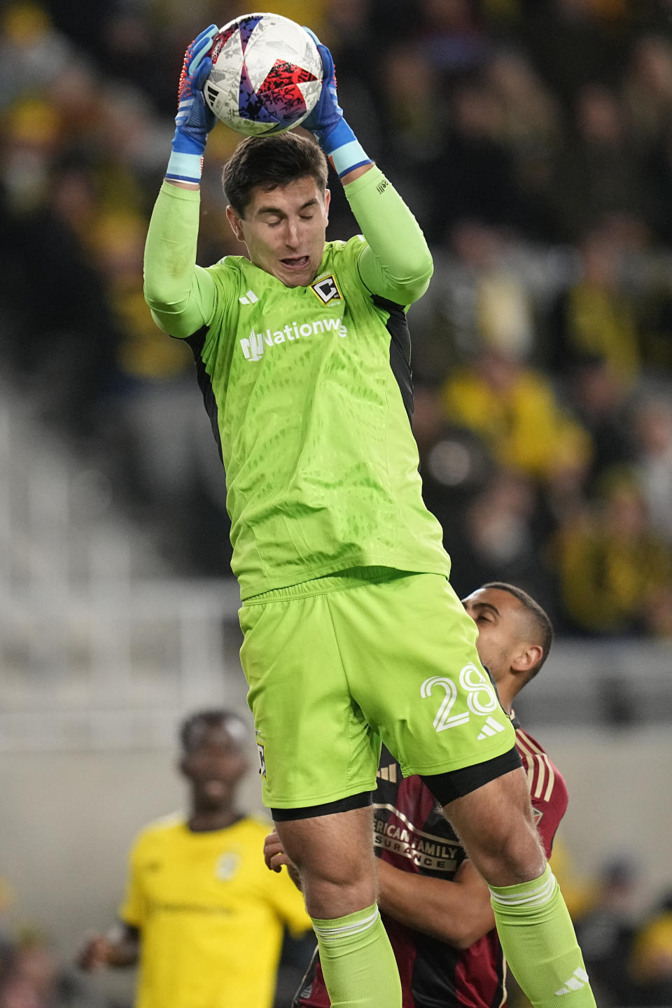 Columbus Crew goalkeeper Patrick Schulte (28) makes a save in front of Atlanta United's Giorgos Giakoumakis, right, in the first half of an MLS playoff soccer match, Wednesday, Nov. 1, 2023, in Columbus, Ohio. (AP Photo/Sue Ogrocki)