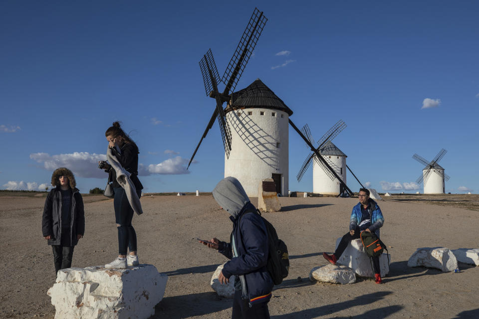 In this April 11 2019, photo, teenagers gather around windmills in Campo de Criptana, near Ciudad Real, central Spain. With nearly 400,000 voters in a country of 37 million, Ciudad Real is a microcosm of the weight of rural areas in national politics. In the last general election, in 2016, three of the five deputies chosen by the province went to the PP conservatives and two to the Socialists. But reflecting the crisis of bipartisan politics, polls are predicting now at least two seats for the Socialists and one for PP, with the remaining two going for a few thousand votes of difference to either two of the once-dominant parties, or even a split between the center-right Citizens and Vox. (AP Photo/Bernat Armangue)