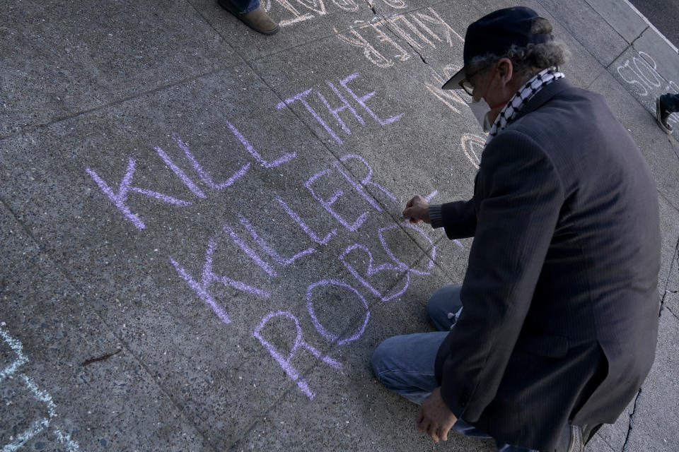 A man writes on the sidewalk while taking part in a demonstration about the use of robots by the San Francisco Police Department outside of City Hall in San Francisco, Monday, Dec. 5, 2022. The unabashedly liberal city of San Francisco became the unlikely proponent of weaponized police robots this week after supervisors approved limited use of the remote-controlled devices, addressing head-on an evolving technology that has become more widely available even if it is rarely deployed to confront suspects. (AP Photo/Jeff Chiu)