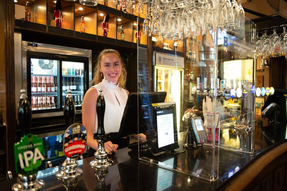 Windsor, Berkshire, UK. 4th July, 2020. A member of staff serves drinks behind a Perspex screen at the Wetherspoon King and Castle pub in Windsor, Berkshire. Today the pub opened for the first time since the Coronavirus lockdown in March. Credit: Maureen McLean/Alamy Live News