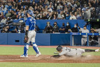 Toronto Blue Jays catcher Tyler Heineman (22) looks on as New York Yankees' Tim Locastro (33) scores on a single to center field by Gleyber Torres during the ninth inning of a baseball game in Toronto, Monday, May 2, 2022. (Christopher Katsarov/The Canadian Press via AP)