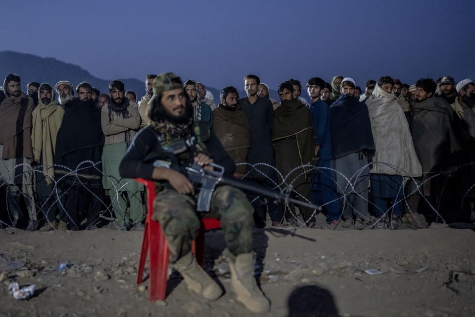 A Taliban fighter stands guard as Afghan refugees line up to register in a camp near the Pakistan-Afghanistan border in Torkham, Afghanistan, Saturday, Nov. 4, 2023. Many Afghans have lived for decades in Pakistan, driven there by successive wars at home. When the order was announced, hundreds of thousands feared arrest and fled back to Afghanistan. Often Pakistani authorities prevented them from taking anything with them, they say. (AP Photo/Ebrahim Noroozi)