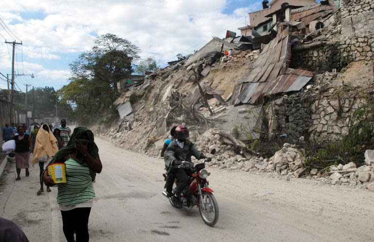 Haitians pass a destroyed building on January 13, 2010 in Port-au-Prince, one day after a 7.0 magnitude earthquake