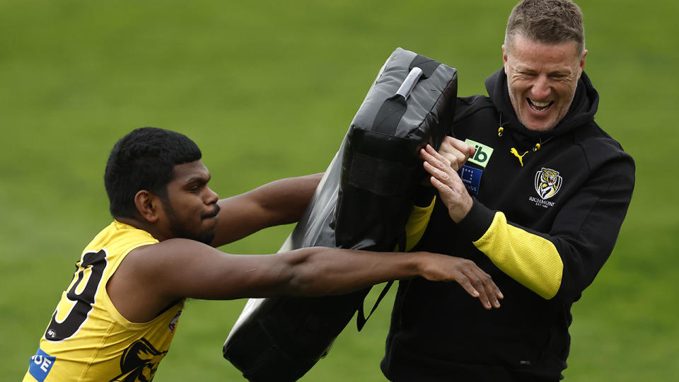 Damien Hardwick laughs as Tigers player Maurice Rioli runs into him during a drill.