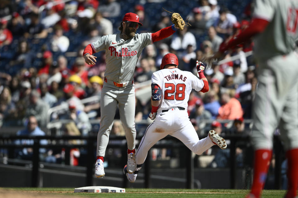 Washington Nationals' Lane Thomas (28) is safe at first with a single against Philadelphia Phillies first base Bryce Harper (3) during the fifth inning of a baseball game, Sunday, April 7, 2024, in Washington. (AP Photo/Nick Wass)
