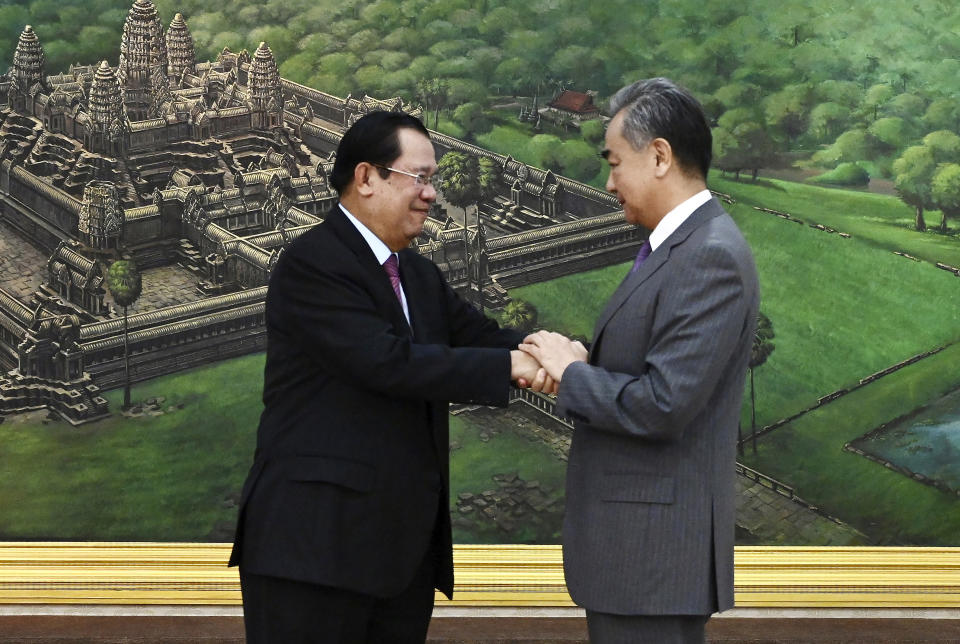 In this photo provided by Kok Ky/Cambodia's Government Cabinet, Cambodian Prime Minister Hun Sen, left, shakes hands with Chinese Foreign Minister Wang Yi during a welcome meeting at the Peace Palace in Phnom Penh, Cambodia, Wednesday, Aug. 3, 2022. (Kok Ky/Cambodia's Government Cabinet via AP)