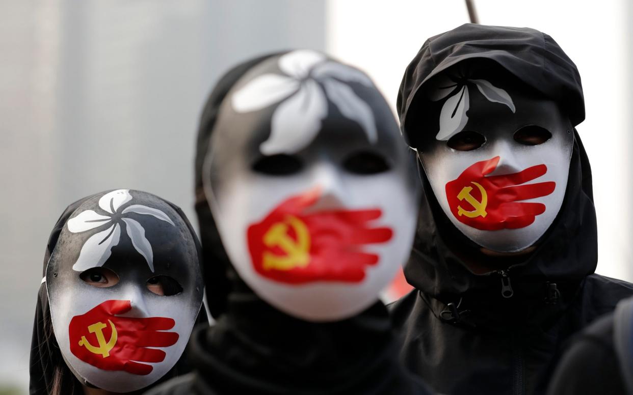 People wearing masks stand during a rally to show support for Uighurs and their fight for human rights in Hong Kong - AP