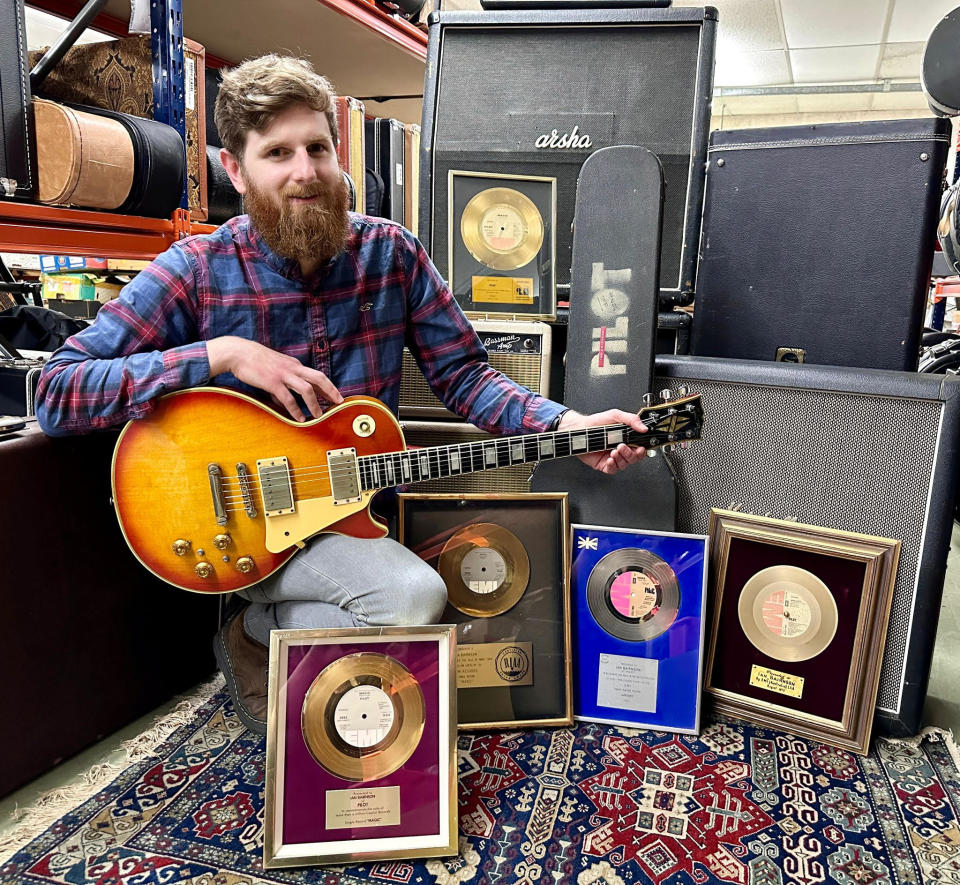 Auctioneer Luke Hobbs with Ian Bairnson’s guitar and equipment (Gardiner Houlgate/PA)