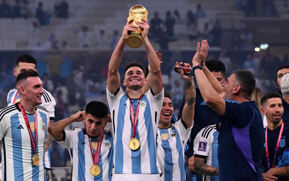 Julian Alvarez lifts the FIFA World Cup Trophy as he celebrates with teammates winning the Qatar 2022 World Cup final - AFP