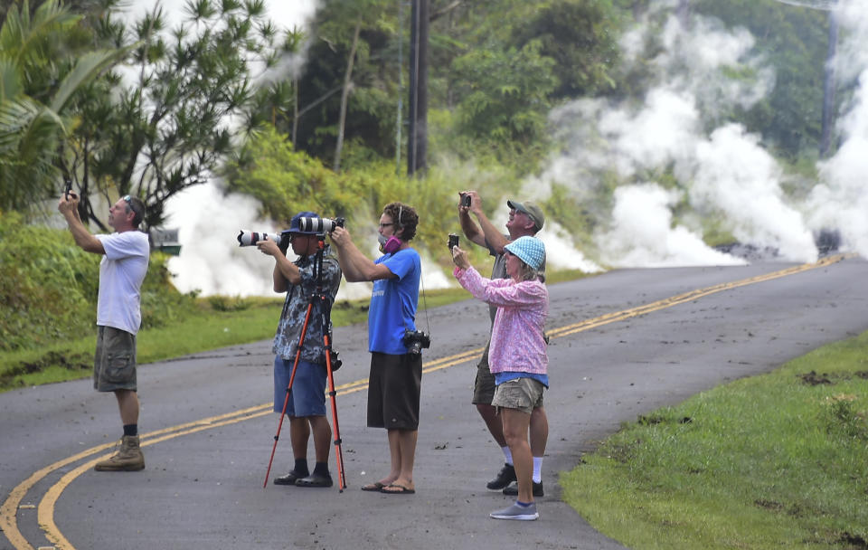 People take photos of lava as steam rises from a fissure in Leilani Estates&nbsp;on Friday.