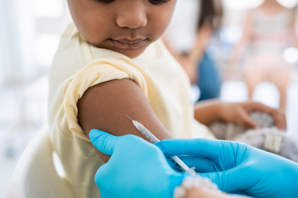 Immunisation. Protecting children from diseases. Close-up nurse in medical gloves giving injection to little patient. Brave boy getting a flu shot at doctor's office and looking at needle