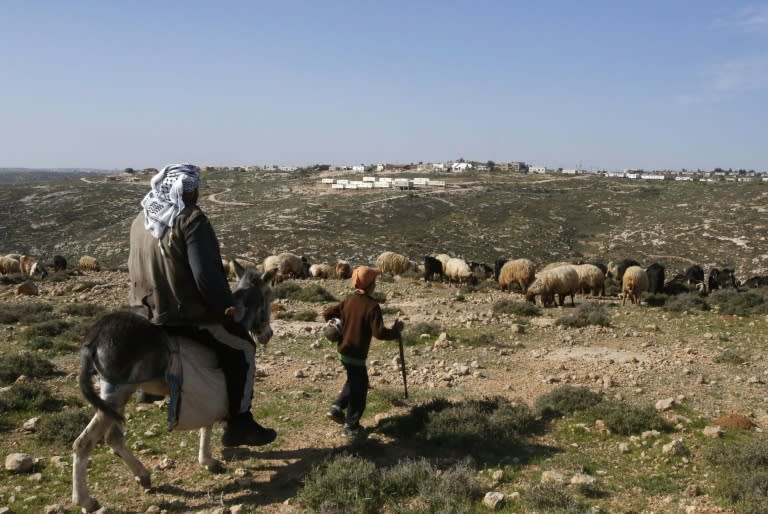 A Palestinian man and a child are seen in the village of Sair near the Israeli settlement of Metzad