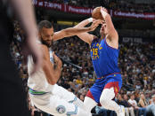 Minnesota Timberwolves center Rudy Gobert, left, reels back after he was hit in the chest as Denver Nuggets center Nikola Jokic drove to the basket in the first half of an NBA basketball game Friday, March 29, 2024, in Denver. (AP Photo/David Zalubowski)