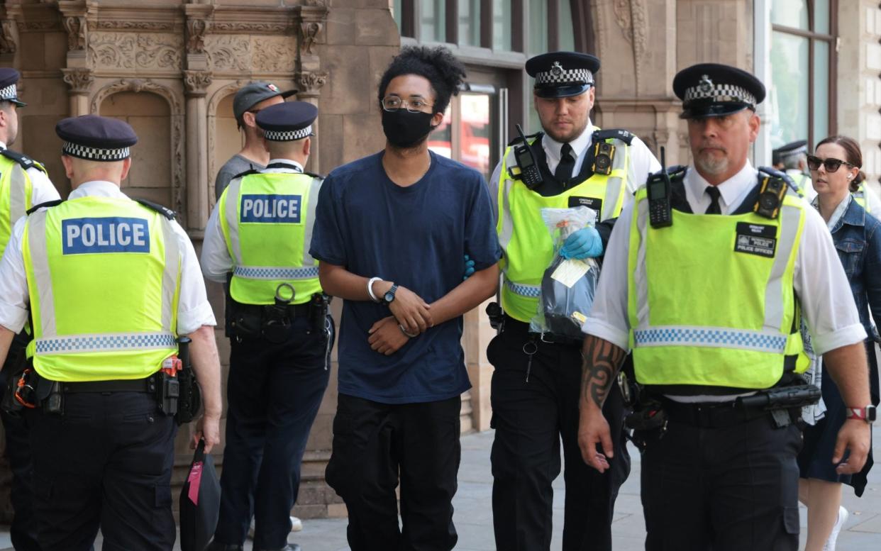 Police with a man at the protest on Wednesday morning