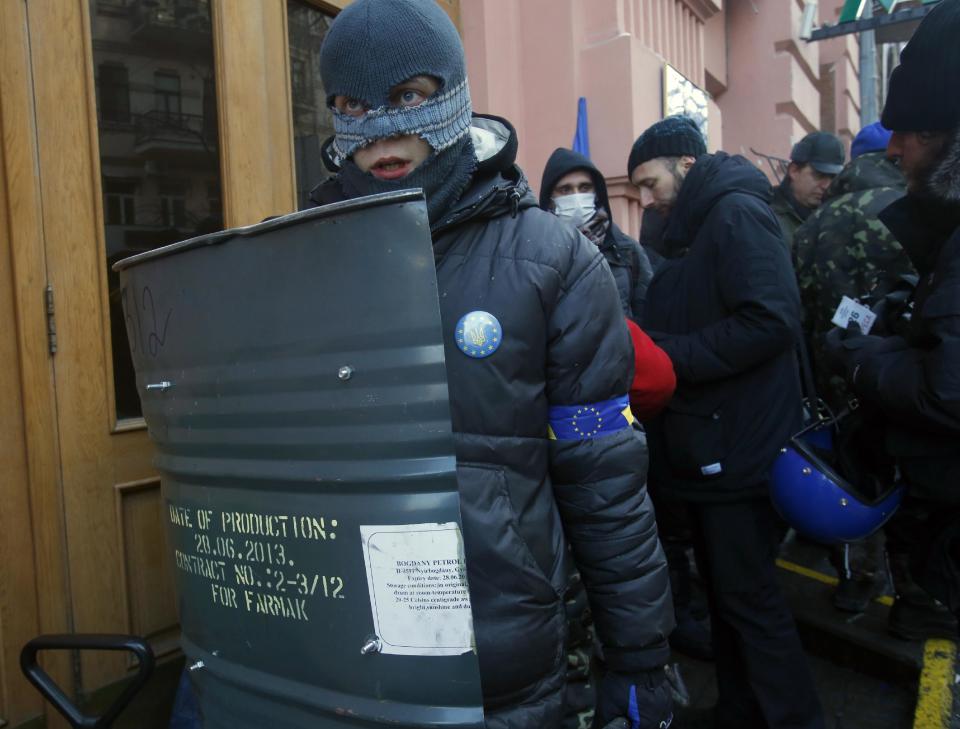 Protesters stand guard outside the Justice Ministry in central Kiev, Ukraine, Monday, Jan. 27, 2014. Ukraine's justice minister is threatening to call for a state of emergency unless protesters leave her ministry building, which they occupied during the night. The seizure of the building early Monday underlined how anti-government demonstrators are increasingly willing to take dramatic action as they push for the president's resignation and other concessions. (AP Photo/Sergei Grits)