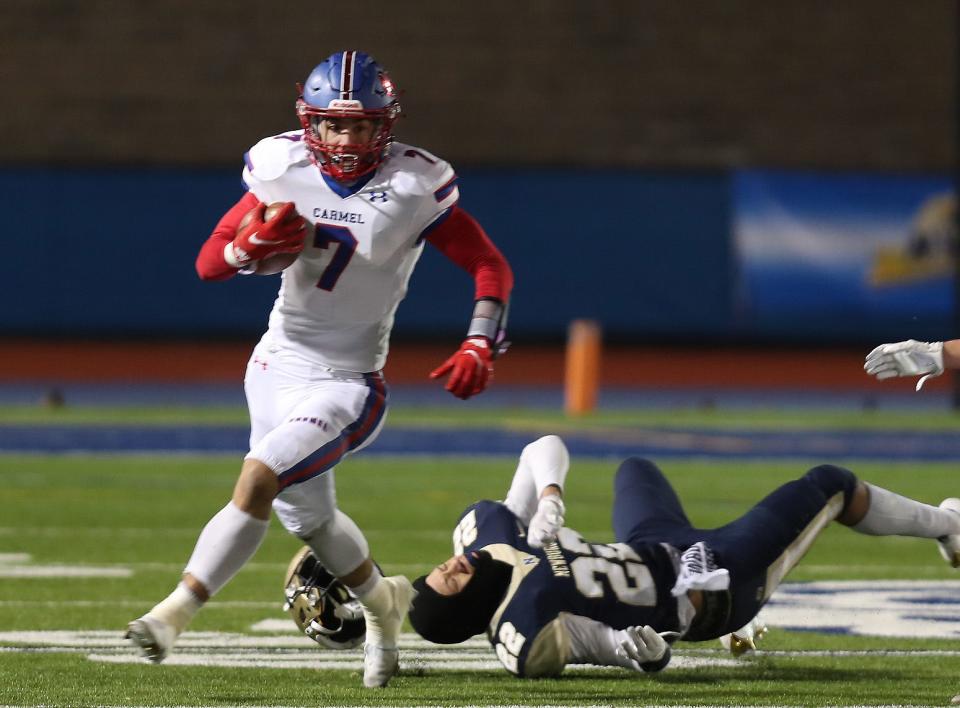 Carmel's Andrew Fiore (7) runs by Newburgh's Marcellus Lockklary (22) during the Class AA state semifinal at Middletown High School Nov. 27, 2021.