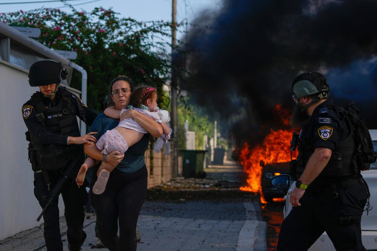 Police officers evacuate a woman and a child from a site hit by a rocket fired from the Gaza Strip, in Ashkelon, southern Israel (Copyright 2023The Associated Press All rights reserved)