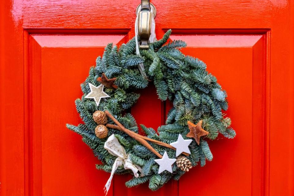 A Christmas wreath hanging on a red front door