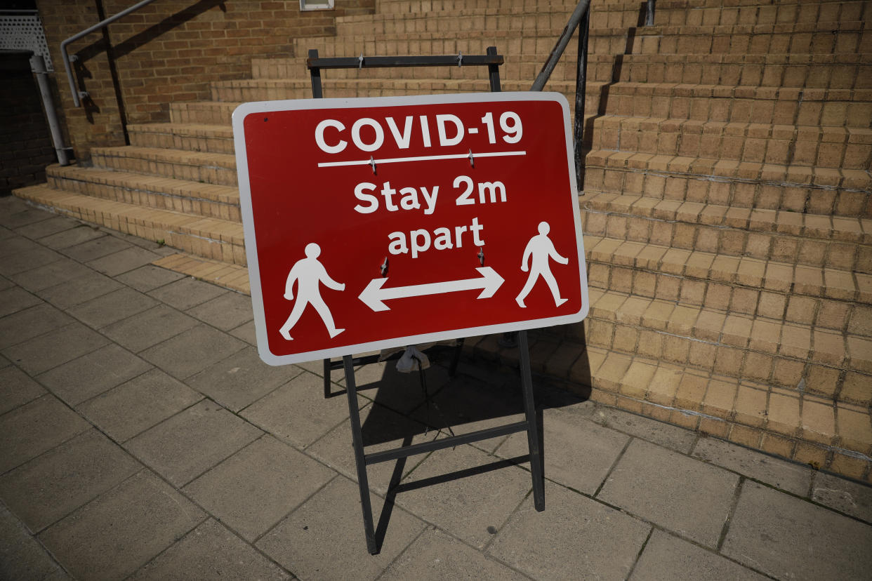 A sign requesting people stay two metres apart is displayed in Kingston upon Thames, south west London, Monday, June 22, 2020. The two-metre social distancing rule will be under review as the UK relax coronavirus lockdown measures implemented to stem the spread of the virus. (AP Photo/Matt Dunham)