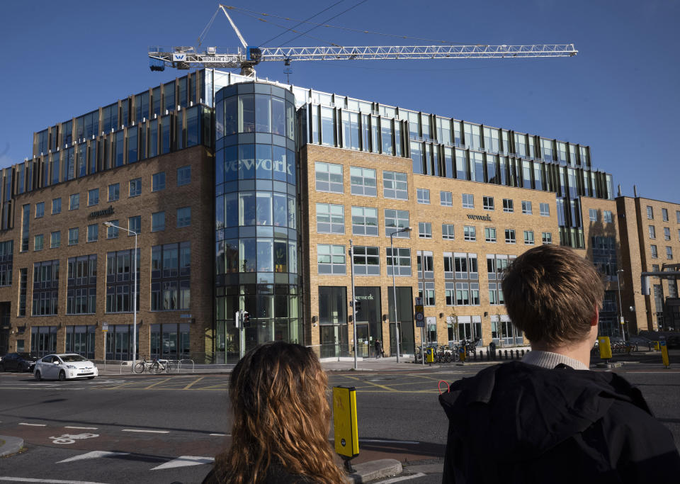 In this Oct. 6, 2019, photo people walk by WeWork offices in Dublin, Ireland. The Wall Street Journal is reporting on Tuesday, Oct. 22, that WeWork is being taken over by the Japanese investment bank that invested billions in the company before its botched effort to go public. (AP Photo/Mark Lennihan)