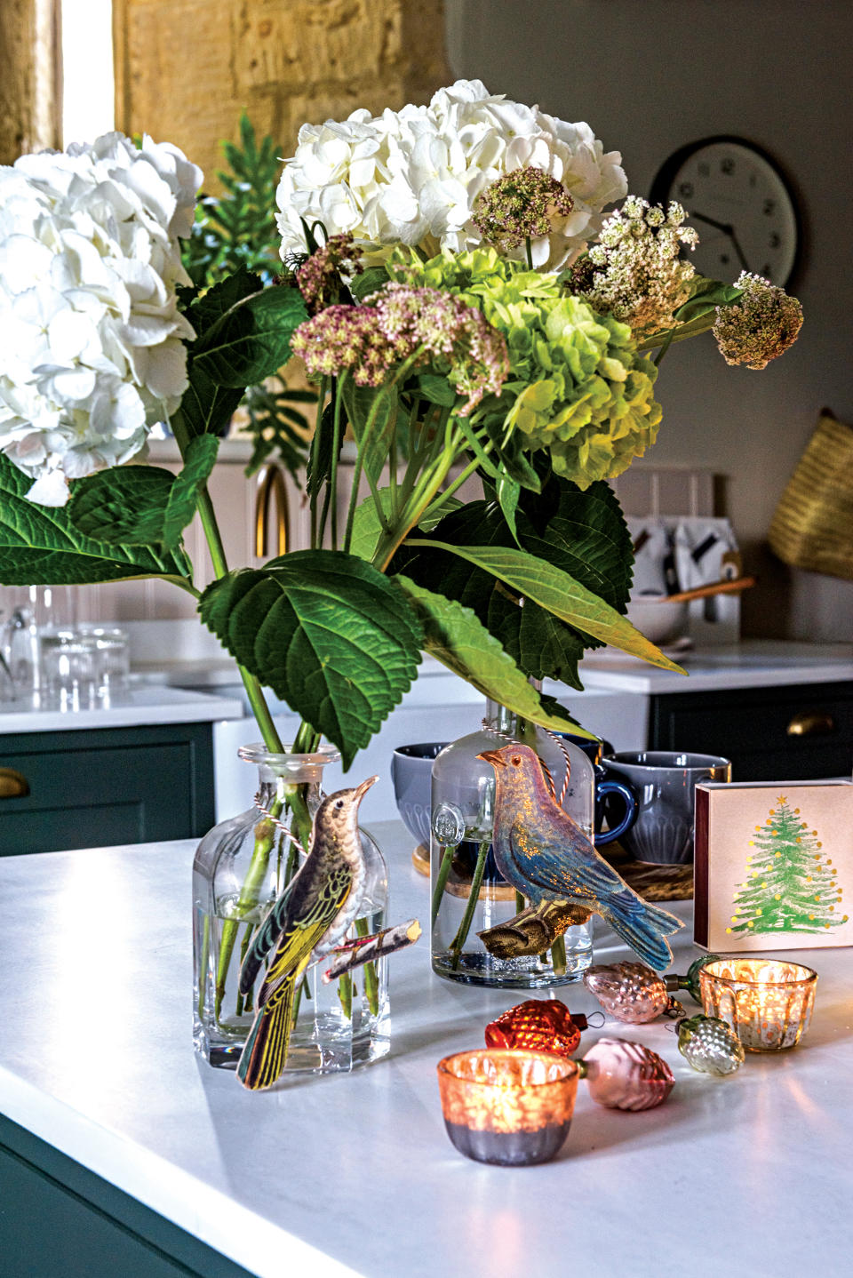 Close up of glass vase with Hydrangeas and candles on kitchen counter