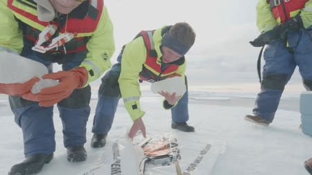 A scientist from the U.S.-led Northwest Passage Project picks up ice cores drilled from the Canadian Arctic during an 18-day icebreaker expedition that took place in July and August 2019