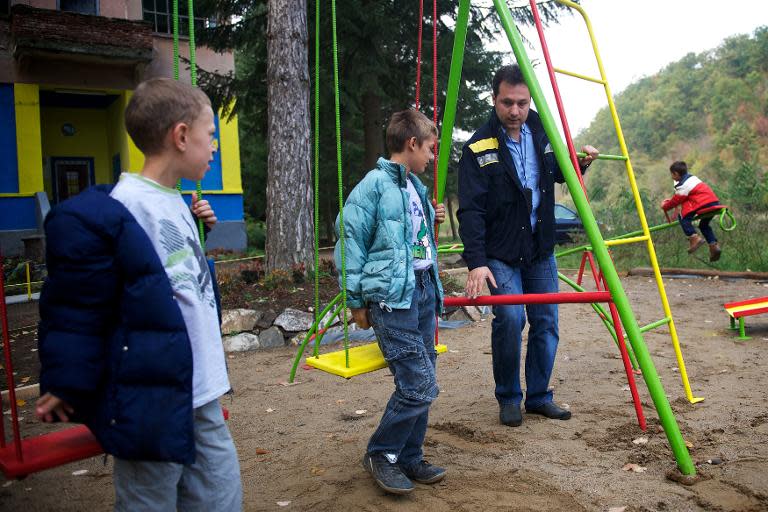 Postman Filip Filipovic (R) checks on October 7, 2013 on a swing in front of his post office in Kursumlijska Banja, some 300 kms south of the capital Belgrade