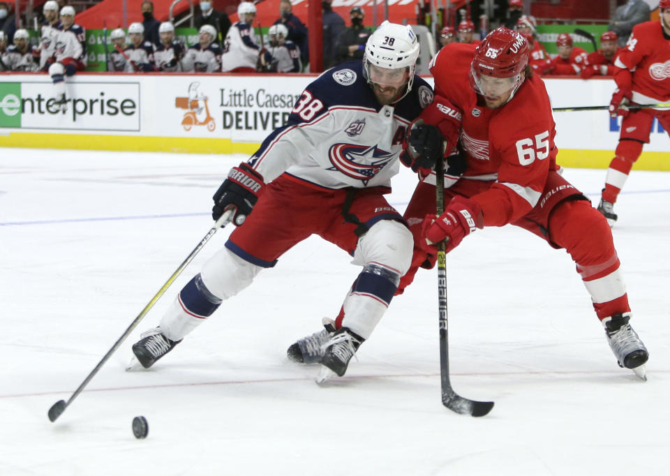 Columbus Blue Jackets center Boone Jenner (38) tries to hold off Detroit Red Wings defenseman Danny DeKeyser (65) during the third period of an NHL hockey game Tuesday, Jan. 19, 2021, in Detroit. (AP Photo/Duane Burleson)