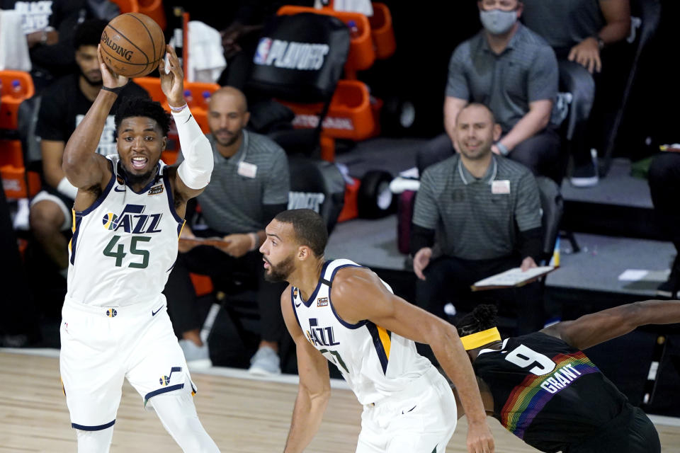 Utah Jazz's Donovan Mitchell (45) passes the ball as teammate Rudy Gobert, center, and moves up court against Denver Nuggets' Jerami Grant (9) during the first half of an NBA basketball first round playoff game, Monday, Aug. 17, 2020, in Lake Buena Vista, Fla. (AP Photo/Ashley Landis, Pool)