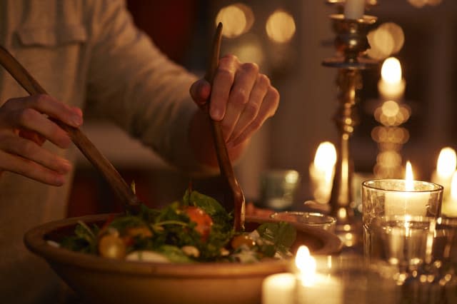 Man taking salad from bowl at candlelight dinner