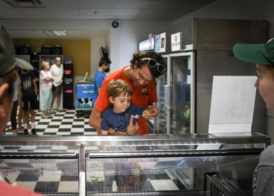 Calder Wilmers, 3, of San Francisco and father Adam visit the MSU Dairy Store Friday, July 8, 2022, on the campus of Michigan State University. Calder was happy with his Superman ice cream sample. Adam is a 2010 graduate of MSU's human resources program. The father and son explored campus while visiting family in the area.
