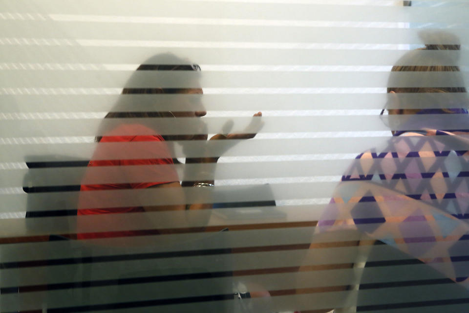 In this Aug. 16, 2019 photo, trans activist Kenya Cuevas, left, speaks on a cellphone accompanied by psychologist Catherinne Marquez, at the Victim Assistance Center, in Mexico City. Cuevas was at the center to seek reparation for the damage done as a victim and witness to the 2016 murder of her friend and fellow trans sex worker Paola Buenrostro. (AP Photo/Ginnette Riquelme)