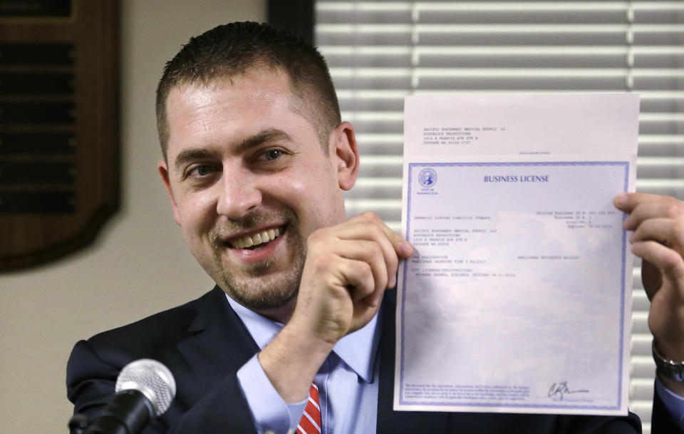 Sean Green displays his new Washington state legal marijuana license at a presentation Wednesday, March 5, 2014, in Olympia, Wash. Green, a medical marijuana dispensary operator from Spokane, was issued the producer-processor license under the state's recreational pot law at the Liquor Control Board meeting. (AP Photo/Elaine Thompson)