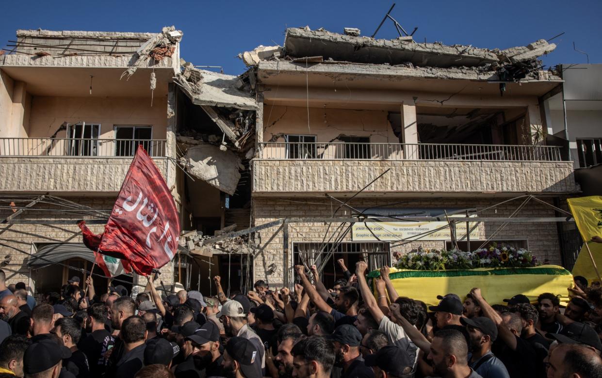 Mourners carry the coffin of Hezbollah fighter Husein Mohamad Choukair, who was killed in an Israeli drone strike in southern Lebanon on Friday, past rubble from a destroyed house during his funeral on Saturday