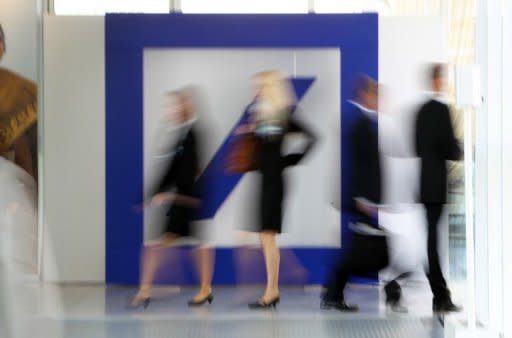 People walk by the Deutsche Bank logo in Frankfurt am Main. The health of 15 of the world's largest financial institutions was called into serious question, as Moody's downgraded their credit ratings, citing exposure risk and Europe's economic woes