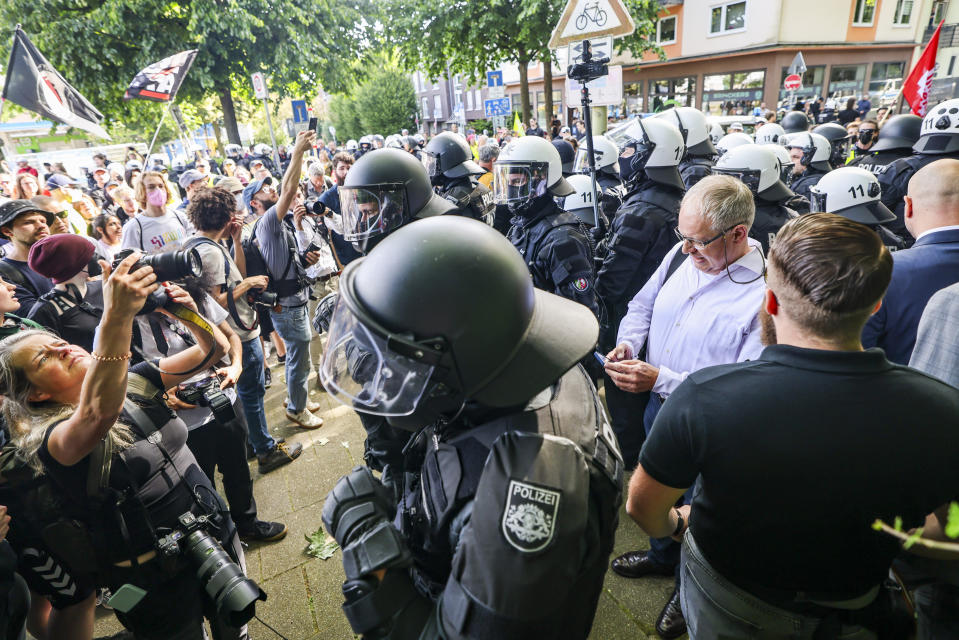 Not far from the Grugahalle, a group of AfD politicians, right, are recognized and surrounded by counter-demonstrators, as the police form a protective ring, in Essen, Germany, Saturday, June 29, 2024. The two-day national party conference of the AfD is taking place in the Grugahalle, including the election of the federal executive committee. Numerous organizations have announced opposition to the meeting and more than a dozen counter-demonstrations. (dpa via AP)