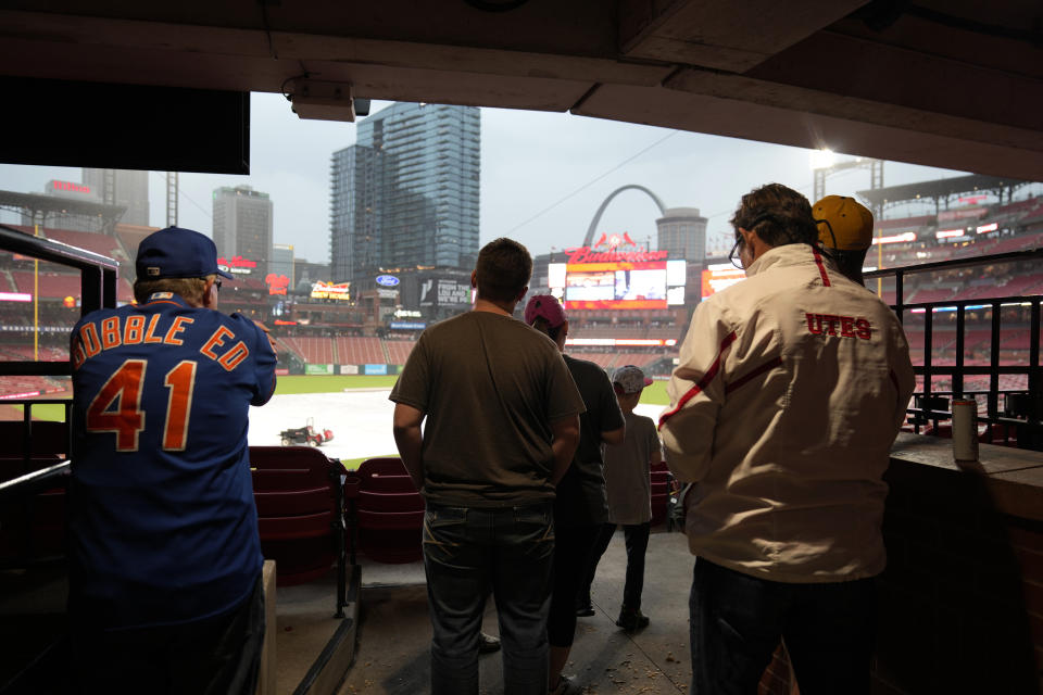 Fans seek shelter in the concourse of Busch Stadium as they wait for the start of a weather delayed baseball game between the St. Louis Cardinals and the New York Mets Wednesday, May 8, 2024, in St. Louis. (AP Photo/Jeff Roberson)