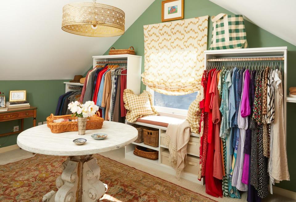 a closet with hanging clothes and a table in the middle