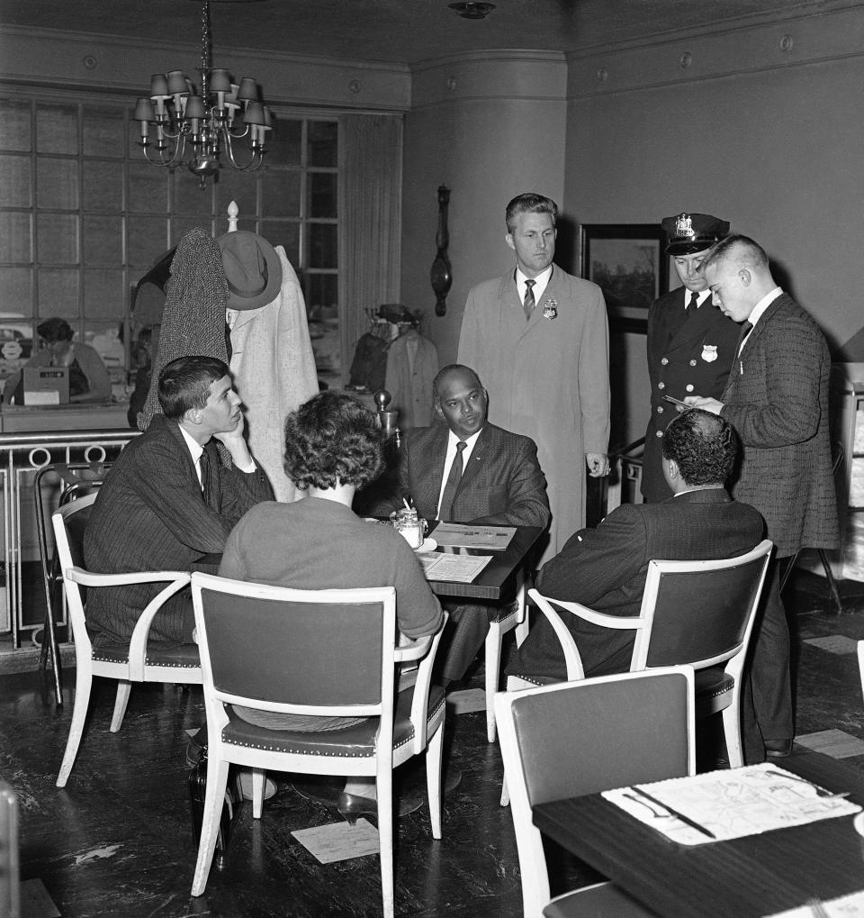 In this file photo, John Anderson, standing, far right, assistant manager of Hooper's Restaurant in Baltimore, reads the state's trespass ordinance to a group of demonstrators who were among hundreds staging "sit-ins" Saturday, Nov. 11, 1961 in Baltimore restaurants. Demonstrators seated at the restaurant table are William Hansen of Cincinnati, Miss Barbara Jacobs of Baltimore, the Rev. Logan Kearse of Baltimore and William Shaw, Baltimore real estate operator. Police are not identified. The four later were arrested.