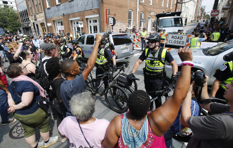 Demonstrators confront police at the intersection where Heather Heyer was killed last year as they mark the anniversary of the Unite the Right rally in Charlottesville, Va., Sunday, Aug. 12, 2018. On that day, white supremacists and counterprotesters clashed in the city streets before a car driven into a crowd struck and killed Heyer. (AP Photo/Steve Helber)
