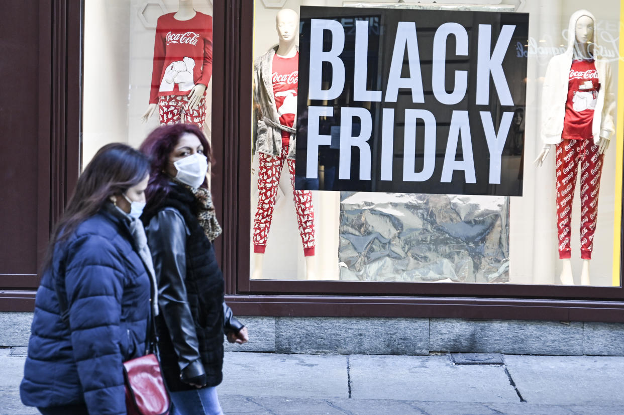 TURIN, ITALY - NOVEMBER 24: Passers-by in protective masks walk past a shop with "Black Friday" signs on a central street in Turin on November 24, 2020 in Turin, Italy. While the whole country is in lockdown of varying degrees between regions, the contagions seems to be dropping.  (Photo by Diego Puletto/Getty Images)